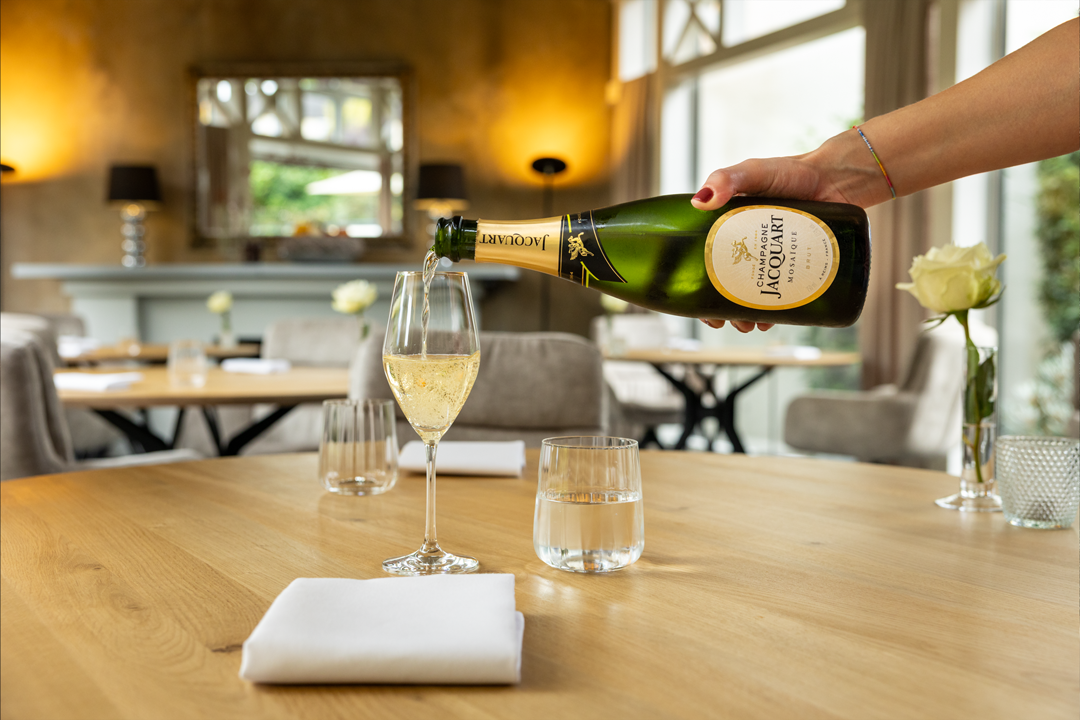 Auf einem Tisch bei Tante Anna wird ein Glas Champagner kredenzt.